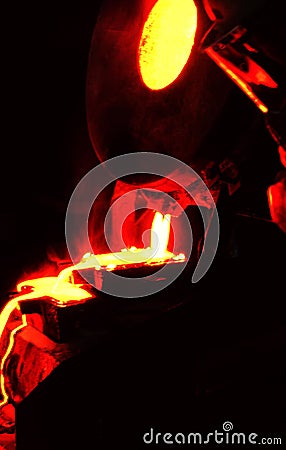 Red hot glowing molten Gold being poured into ingot mold Stock Photo