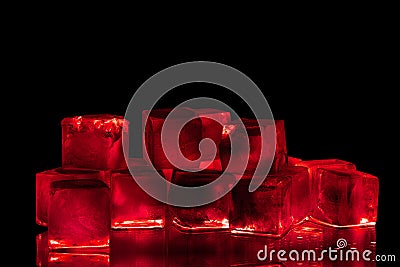 Red ice cubes on black background closeup, transparent frozen burgundy wine color water with red backlight and reflection Stock Photo