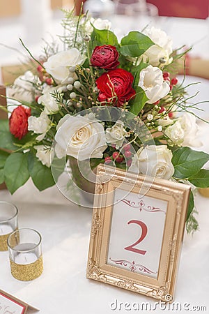 Red and ivory floral arrangement prepared for reception, wedding table with candle and setting, winter concept Stock Photo