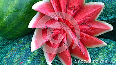 Red juicy cut watermelon in a form of flower on green background for sales. Selling farm products in a local market. Concept of fo Stock Photo