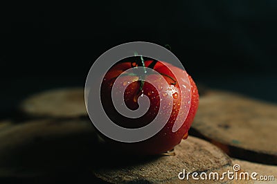 Red juicy and desirable tomato on a piece of wood on a black background Stock Photo