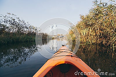 Red kayak rowing towards modern buildings on the waters of Dnipro river in Kyiv, Ukraine Stock Photo