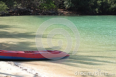 Red Kayak on the tropical white sand beach with sea waves. Scenic relaxing scenery Stock Photo