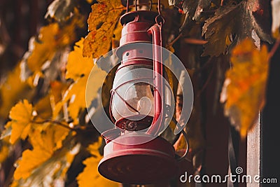 Red kerosene lamp on the fence with leaves Stock Photo