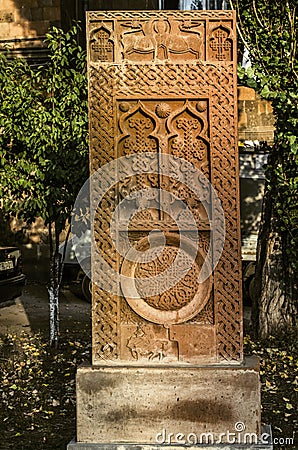 Red khachkar with animal reliefs, arches with crosses and the figure of a Saint on a horse on the alley of stone crosses in Gyumri Stock Photo