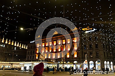 Red knitted hat in foreground at Paradeplatz at christmastime at night with blurred illuminated lights Editorial Stock Photo