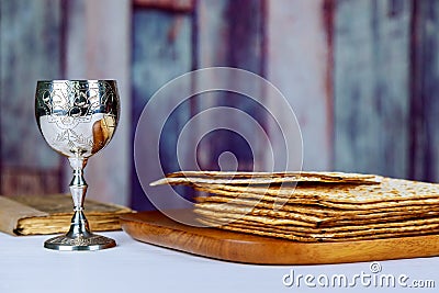 Red kosher wine with a white plate of matzah or matza and a Passover Haggadah on a vintage wood background presented as a Passover Stock Photo