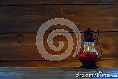 Red Lamp with a candle on the background of a wall lined with brown wood. Stock Photo