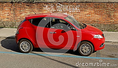 Red Lancia Ypsilon, city car of Fiat Group, on brick wall background. Editorial Stock Photo