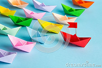 Red leader paper ship leading among others on blue background. Leadership concept Stock Photo