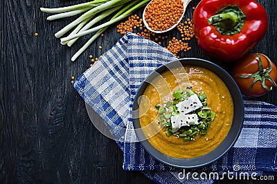 Red lentil cream soup decorated with fresh vegetables and greens. Veggie concept. Proper nutrition. View from above Stock Photo