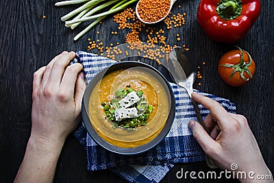 Red lentil cream soup decorated with fresh vegetables and herbs. A man eats soup. Veggie concept. Proper nutrition Stock Photo