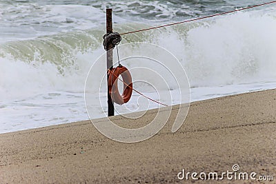 Red lifesaver on beach with breaking huge waves Stock Photo