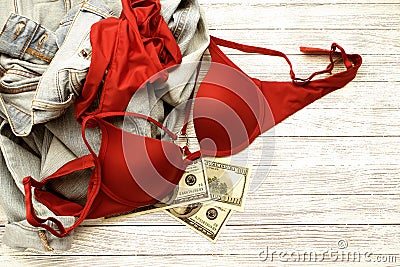 Red lingerie, jeans and money scattered on the floor. Love for money, prostitution concept Stock Photo