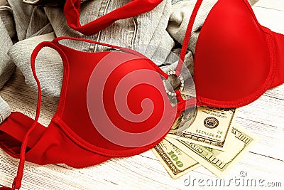 Red lingerie, jeans and money scattered on the floor. Love for money, prostitution concept Stock Photo