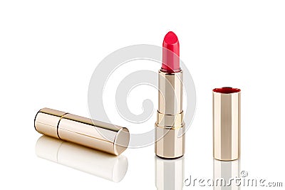 Red lipstick in golden tube on white background with mirror reflection on glass surface isolated close up, shiny gold lipsticks Stock Photo