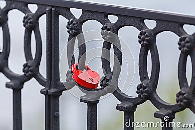 Red lock hanging on forged fence Stock Photo