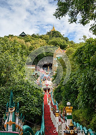 Red long stairs up to the church on the hilltop with dragon statue in tropical rainforest at Wat Ban Tham Stock Photo