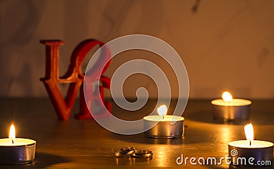 Red love letters on white background on the left wiht two rings and candles Stock Photo