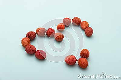Red lychee heart shape on blue White Background.Valentines Day symbol Made of Red lychee Stock Photo