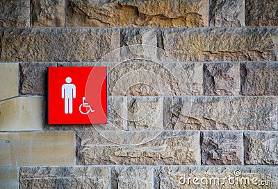 Red male toilet and disabled accessible sign on the old stone brick wall. Stock Photo