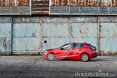 A red Mazda 3 parked in front of an old airplane hangar. Mazda 3. Katowice- Poland, February 15, 2015 Editorial Stock Photo