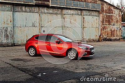 A red Mazda 3 parked in front of an old airplane hangar. Mazda 3. Katowice- Poland, February 15, 2015 Editorial Stock Photo