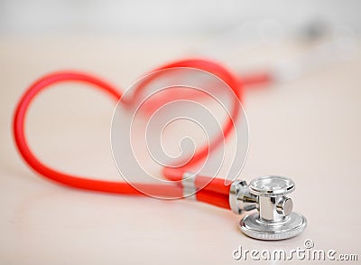 Red medical stethoscope in shape of heart on table Stock Photo