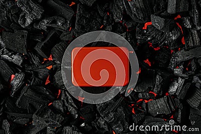 Red metal box on charcoal back. Copy space in a rectangle on a background of hot coals Stock Photo