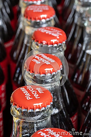 Red metals caps on the top of retro style coca cola bottles carrying the message `Please recycle me`. Stock Photo