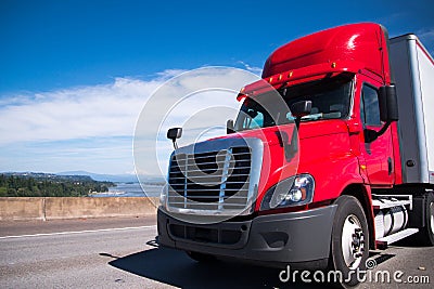 Red modern semi truck with dry van trailer carry commercial cargo for delivery to destination warehouse Stock Photo