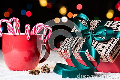 Red mug with candy canes in snow with nicely wrapped present Stock Photo