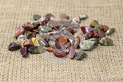 Red and multicolored jasper polished tumblestones on light grey background Narrow focus line, shallow depth of field Stock Photo