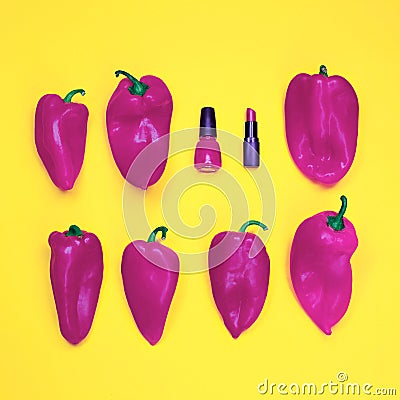 Red nail polish and lipstick, among a large number of red peppers on yellow background Stock Photo