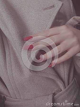 Red nails on the background of a beige coat, autumn photo Stock Photo