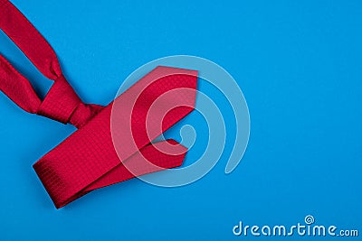 Red neck tie on blue cyan background. Fashionable man`s concept. Place for text. Stock Photo