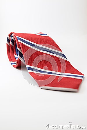 Red neck tie with blue and white stripes layed on white background. Stock Photo