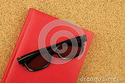 Red notebook and black glases on the cork board Stock Photo