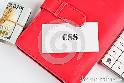 A red notebook displays a card labeled CSS next to a stack of cash and a calculator, illustrating a modern approach to Stock Photo