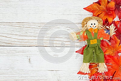 Red and orange fall leaves with a scarecrow on weathered whitewash wood textured background Stock Photo