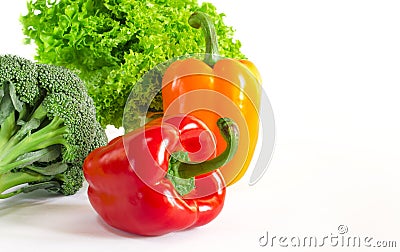Juicy red and orange peppers with a green tail lies next to Bundle of lettuce and broccoli are on a white background Stock Photo