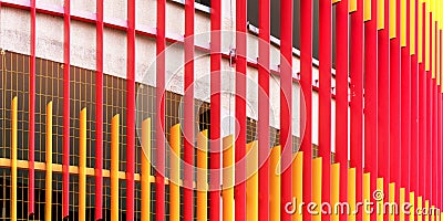 Red and orange scaffolds cover white wall with metal grid Stock Photo