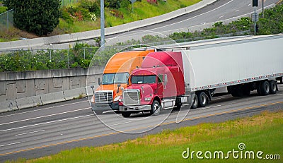 Red orange semi trucks trailers driving highway road together Stock Photo