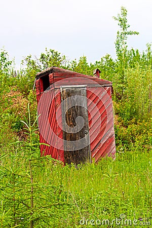 A red outhouse along a hiking trail Stock Photo