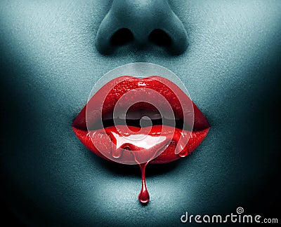 Red Paint dripping, lipgloss drops on sexy lips, bright liquid paint on beautiful model girl`s mouth, Vampire. Halloween. Lipstick Stock Photo