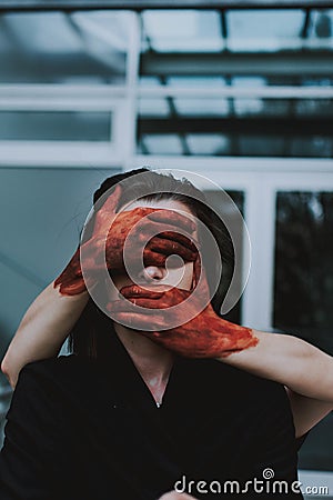 Red painted hands covering the eyes and mouth of a female. Concept of silence Stock Photo