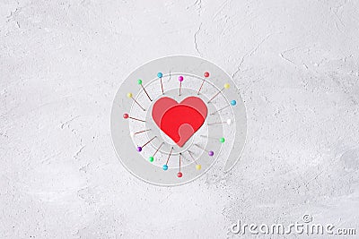 Red paper heart and sewing pins on gray cement background. Hard love, loneliness, divorce, breakup concept Stock Photo