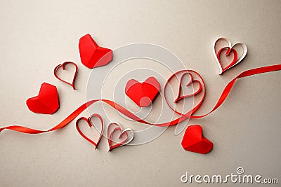 Red paper hearts and silk ribbon on gray background. Valentine`s Day absctract. Symbol of love. Copy space, flat lay Stock Photo