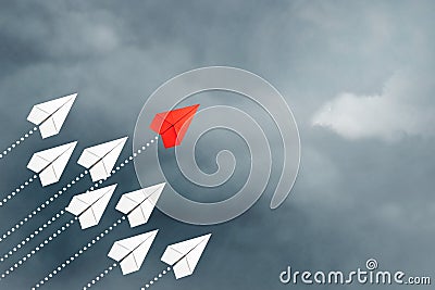 Red paper plane flying in front of a group of whites. Cloudy sky. Leadership concept, teamwork, personnel management. Business. Stock Photo