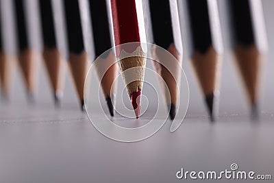 Red pencil stands out from many identical black ones Stock Photo